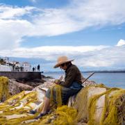 Kvinna lagar ett fiskenät på den grekiska ön Spetses. 