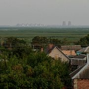 En person cyklar i Nikopol. I bakgrunden syns kärnkraftverket Zaporizjzja.