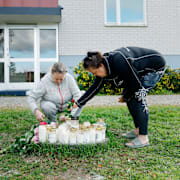 Aktivbild. Annette Nilsson och Mia Olsson tänder ljus utanför huset där en ambulanssjukvårdare blev dödad i tjänsten i Harmånger i Nordanstig kommun på lördagen.