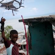 En pojke leker med en drake vid ett förstört hus i Jeremie, Haiti