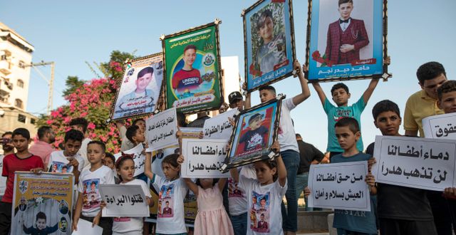 Barn i Gaza håller upp bilder på barnen som dödades under en av de israeliska attackerna mot en kyrkogård i augusti 2022, en av attackerna som granskats i rapporten.  Fatima Shbair / AP