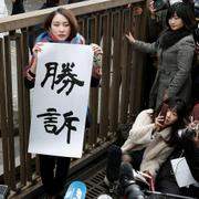 Japanska journalisten Shiori Ito håller upp ett plakat där det står seger.