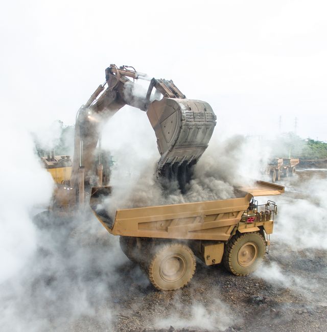Backhoe load warm and smokey slag material into mining dump truck in Nickel Mining in South Sulawesi, Indonesia. Shutterstock