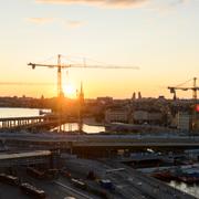 Utsikt över Gamla stan i Stockholm med bussar och lyftkranar och tunnelbana  i solnedgång.