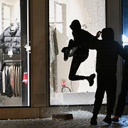 Människor slår sönder ett skyltfönster under upploppen i Paris den 18 oktober 2026.