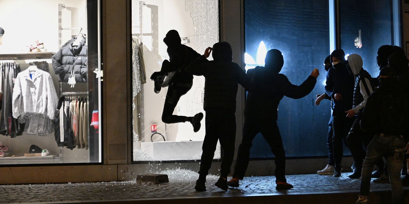 Människor slår sönder ett skyltfönster under upploppen i Paris den 18 oktober 2026.