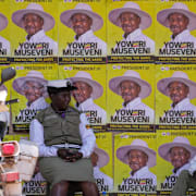 Trafikpoliser sitter framför en vägg med valaffischer för diktatorn Yoweri Museveni.