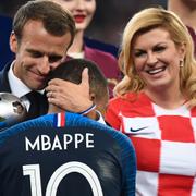 Emmanuel Macron kramar om Kylian Mbappé efter finalen. Till höger Kroatiens president Kolinda Grabar-Kitarović.