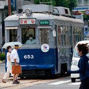 Invånare i Hiroshima går förbi en av stadens spårvagnar. 